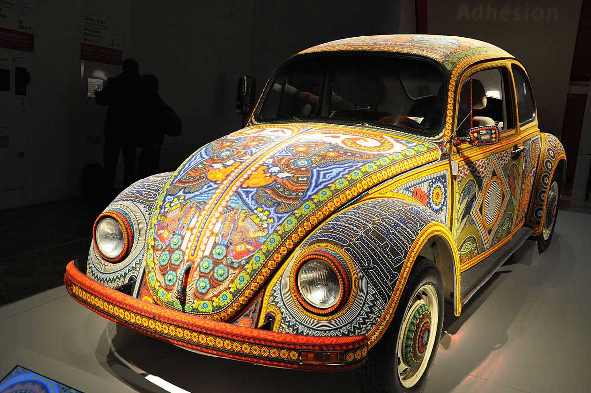 Un auto decorado con chaquiras de colores representando el arte huichol.