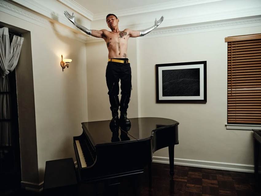 En la imagen, Bohan Phoenix sobre un piano sin camisa y abriendo los brazos. calendario Pirelli 2022