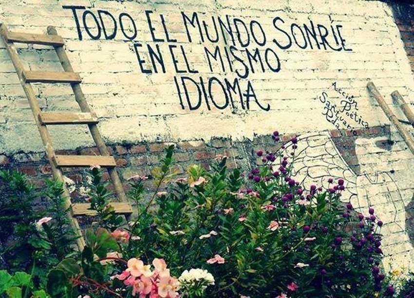 Muro pintado con la frase: Todo el mundo sonríe en el mismo idioma. Acción poética frase Santuario.