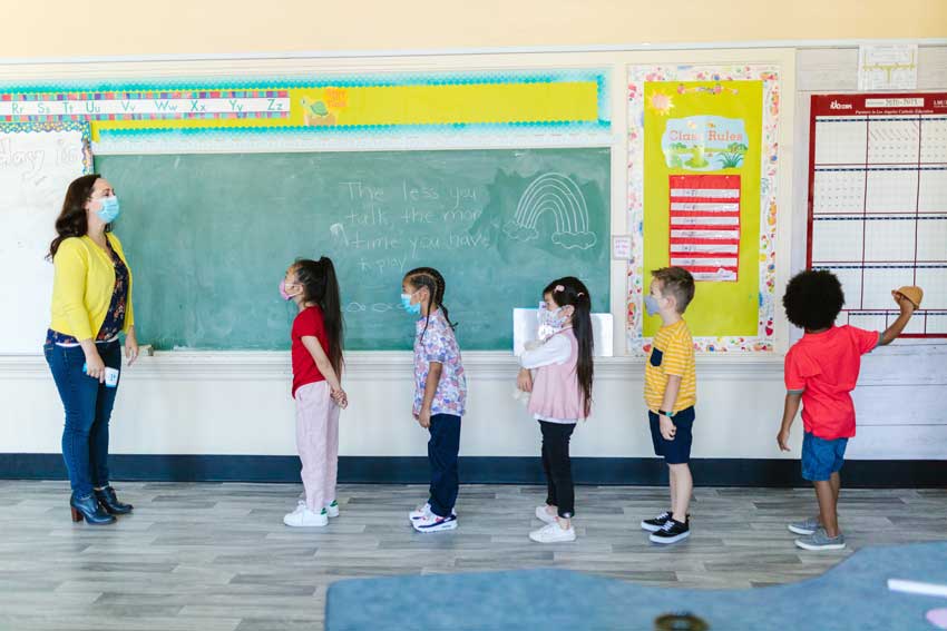 dos niños y tres niñas filados recibiendo instrucciones de su maestra, uno está desconcentrado. Aprendizaje vicario