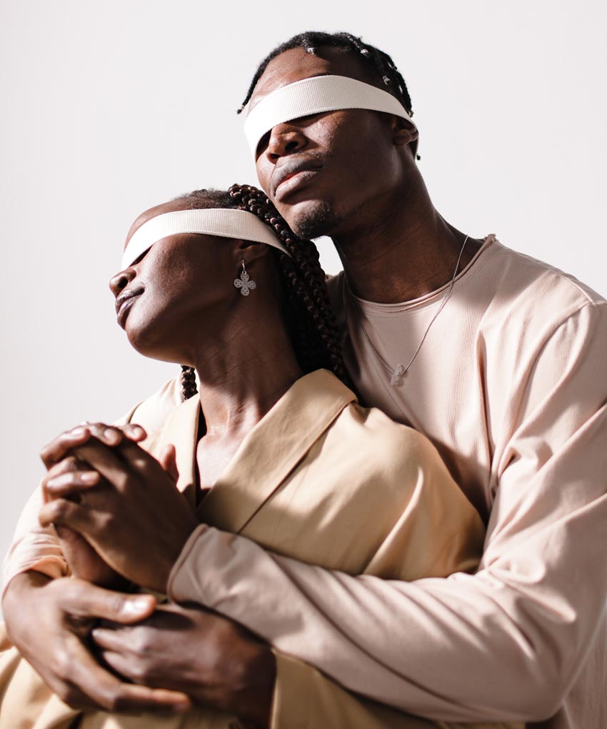 Hombre y mujer de raza negra, hombre abraza desde atrás a la mujer. Ambos tienen los ojos vendados. Efecto Halo