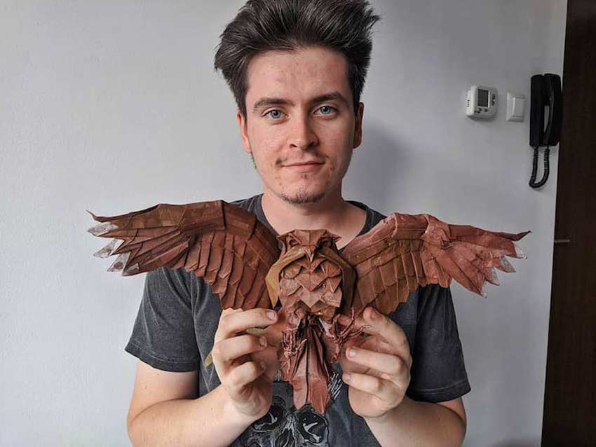 Patrick Alberto Vraja, portando un búho de origami en sus manos con sus alas abiertas. Animales de origami