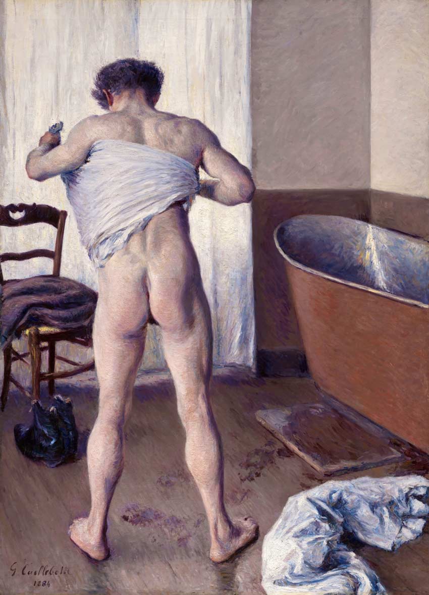 Hombre de espaldas al lado de una bañera secándose. Color de piel blanco, muestra sus gluteos