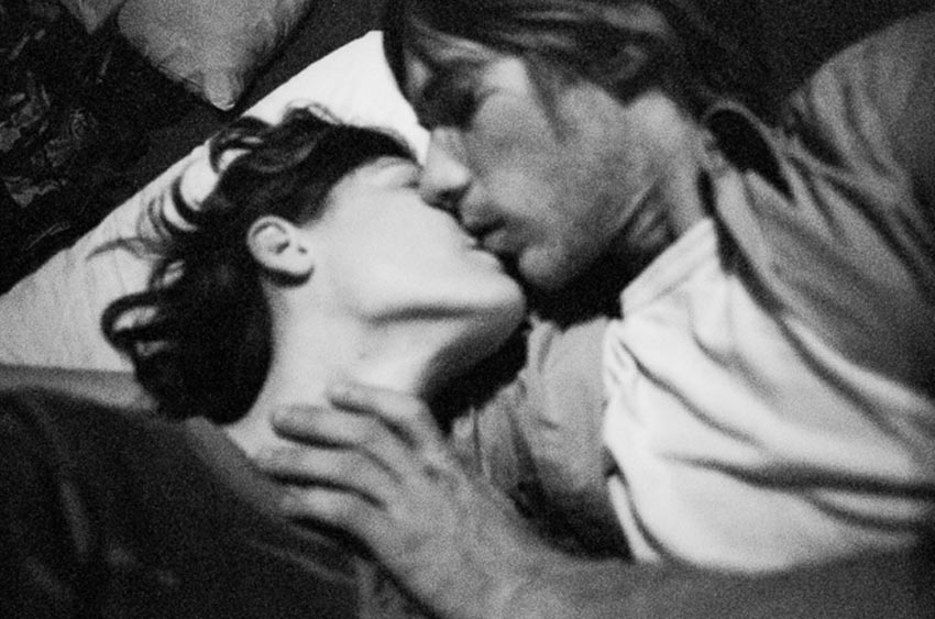 Un hombre y mujer acostados besándose. Foto en blanco y negro.