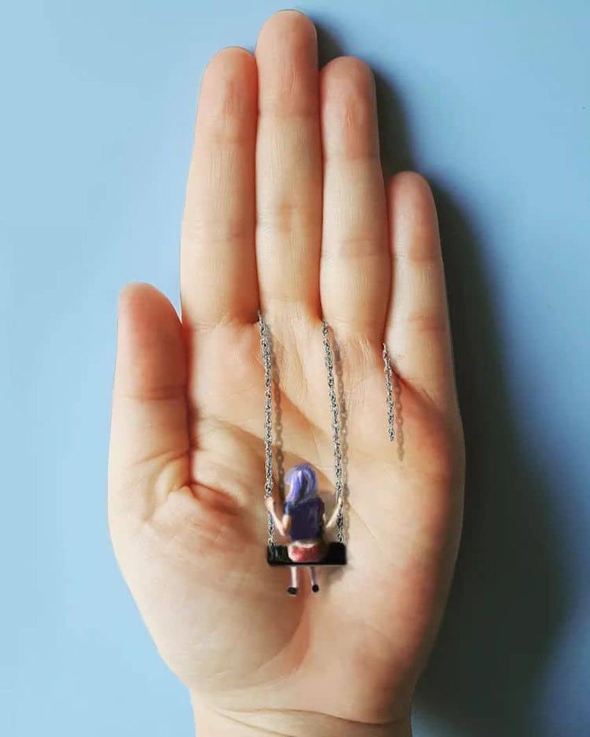 La mano de una artista es su lienzo. pintura de una niña con pelo azul en un columpio.