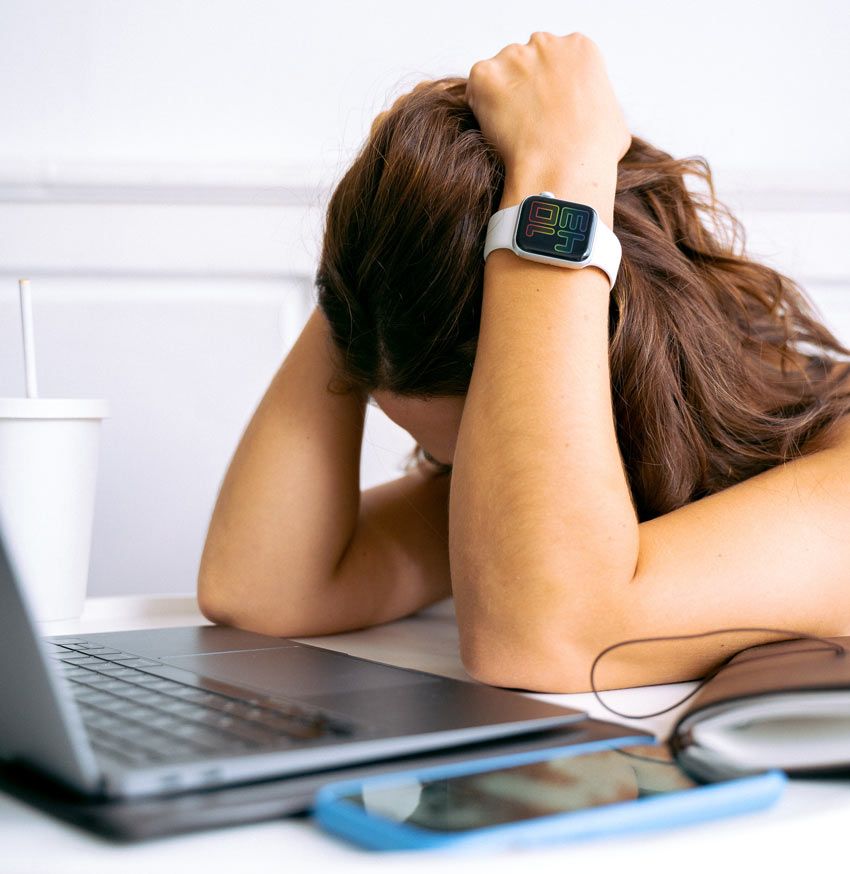 Mujer cansada frente a su laptop. Síndrome del impostor y el agotamiento laboral