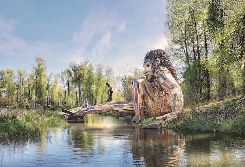 Esculturas de Thomas Dambo gigantes. Troll sentado en un río que a su vez sirve de puente para cruzar