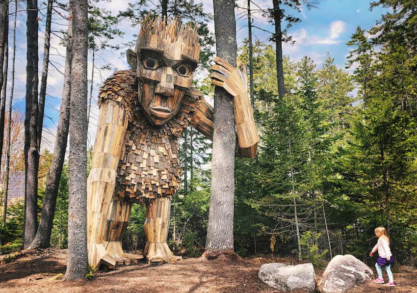 Esculturas de Thomas Dambo gigantes. Troll parado sosteniendo el tronco de un árbol