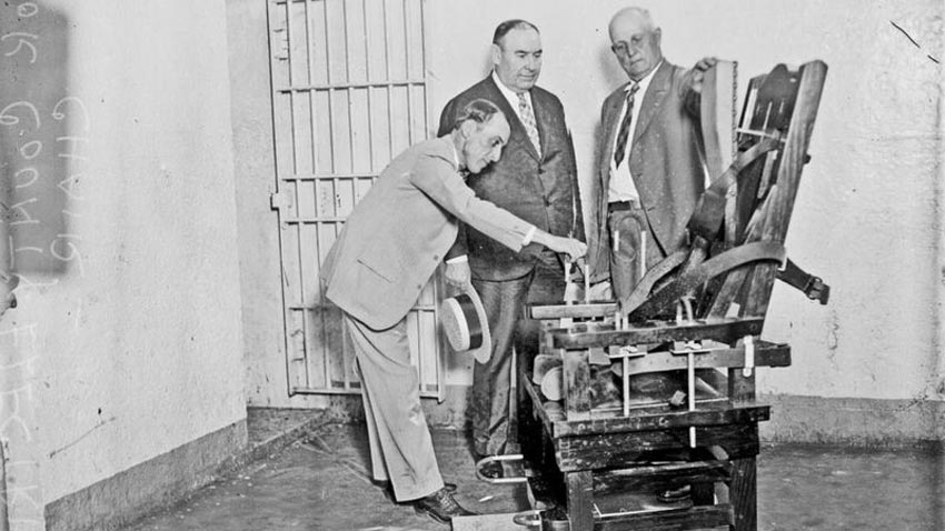 Getty images. Foto en blanco y negro de una silla eléctrica y tres hombres observando.