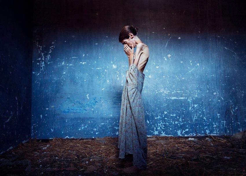Autorretrato Lene Marie Fossen. En la foto una mujer que sufre anorexia con sus manos en la cara en un cuarto con paredes azules