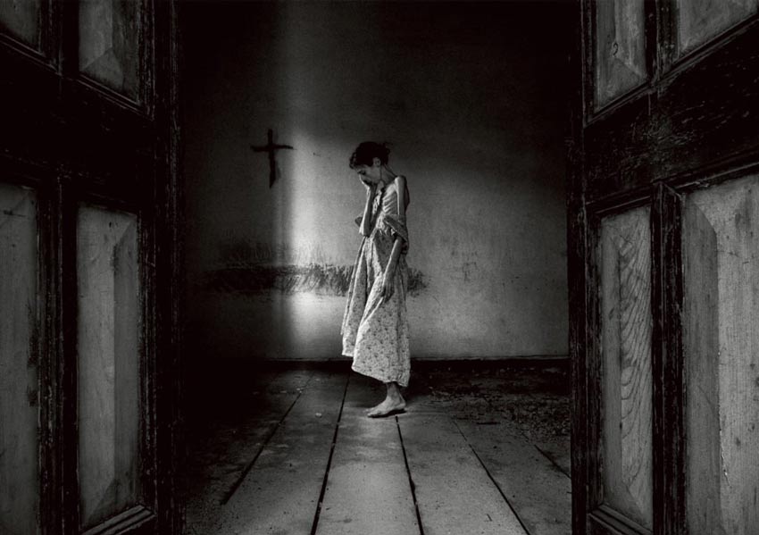 Autorretrato Lene Marie Fossen. En la foto una mujer que sufre anorexia, se sostiene la cara con una mano parada en un cuarto